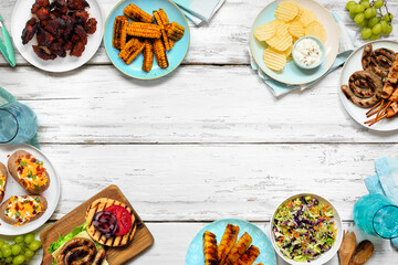 Poster - Summer BBQ or picnic food frame. Burgers, grilled meats, potatoes, smoked corn, fruits, salad and snacks. Top view on a white wood banner background. Copy space.