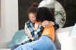 © Wavebreak Media - Lesbian couple embracing on couch, sharing warm hug at home