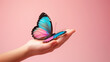 © ArtistiKa - A delicate hand holding a vibrant butterfly with blue and pink wings set against a pink background, representing gentleness and beauty of nature.