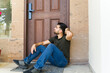 © AntonioDiaz - Young man locked out of his house and sitting and waiting next to his door for someone else to open
