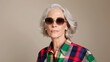 © Luluraschi - chic modern mature caucasian woman wearing sunglasses and vibrant cool plaid shirt, on beige background, elderly fashion model