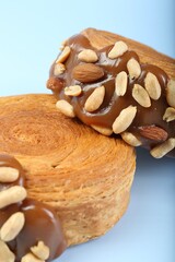 Poster - Supreme croissants with chocolate paste and nuts on light blue background, closeup. Tasty puff pastry
