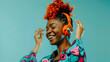 © Generative AI - Young happy female in colorful outfit with orange Afro braids touching headphones while dancing to music against turquoise background : Generative AI