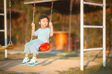 baby girl with happy time in outdoor by swing play on grasses floor in blue dress