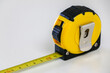 © Adam - Close up of black and yellow retractable tape measure, useful tool for measuring length, width and height. Accuracy and precision concept