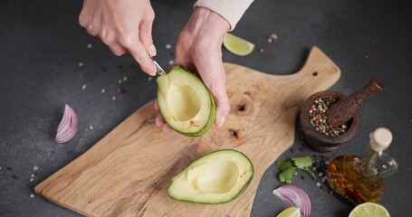 Wall Mural - Woman peeling Halved green avocado fruit while cooking at domestic kitchen