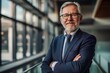 © Iryna - Successful senior executive in a suit, confidently smiling in a modern office building.