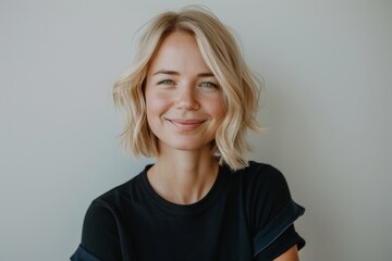 Wall Mural - A close-up portrait of a woman with blonde hair, wearing a black shirt, smiling at the camera