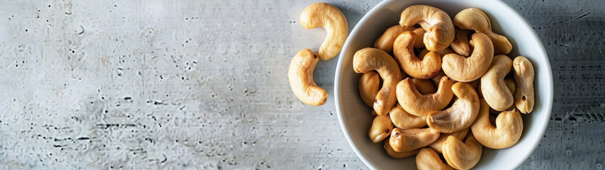 Wall Mural - Cashew nuts in white bowl on textured background