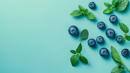 Wall Mural - A blueberry and mint leaf arrangement on a blue background. The blueberries are scattered around the mint leaves, creating a visually appealing and healthy snack