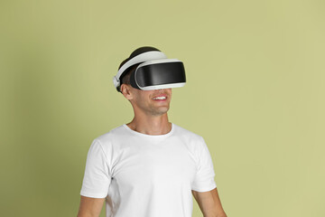 Smiling man using virtual reality headset on light green background