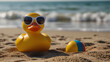 © Halfjoy - Rubber duck facing the camera wearing sunglasses floating in sea sand with ball beach and ocean behind background