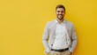 © Bijac - portrait of smiling confident male entrepreneur with hands in pockets yellow background advertising banner