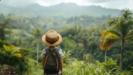 Wall Mural - Traveler child with a straw hat and tourist backpack during a hike in the tropical forest.