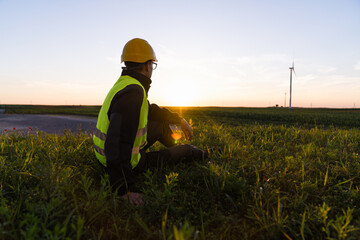 Aufkleber - Worker sits on the grass and looks at wind turbines