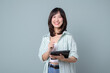 © Jirawatfoto - Portrait of young asian woman, teacher or student with digital tablet and pencil, writing, taking notes, doing her homework, standing over green background