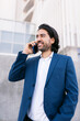© Renata Hamuda - vertical image of smiling Caucasian businessman in blue suit talking on a cell phone outside