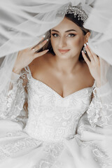 Wall Mural - A woman in a white wedding dress is posing for a picture. She is wearing a tiara and has her hands on her hips. The image has a romantic and elegant mood