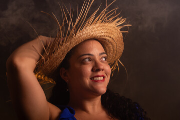 Portrait of beautiful woman wearing a brown colored traditional straw hat. Characterized for the feast of Sao Joao.