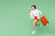 © ViDi Studio - Full body traveler woman wear casual clothes hold passport ticket suitcase bag run fast hurry up isolated on plain green background. Tourist travel abroad in free time rest. Air flight trip concept.