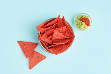 Wall Mural - Bowl with red nachos and tasty guacamole on blue background