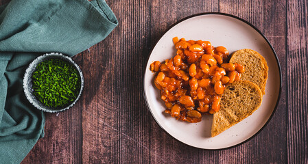 Poster - Plate with baked beans in tomato sauce and rye bread on the table top view web banner