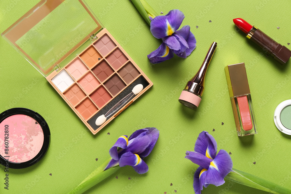 Makeup products with flowers and confetti on green background