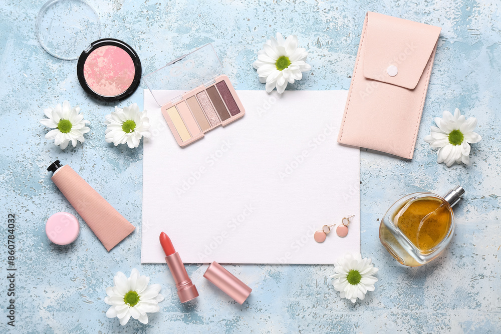 Blank card with makeup products, case for brushes and daisies on blue grunge background