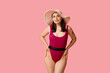 © Pixel-Shot - Beautiful young woman in swimsuit with hat on pink background