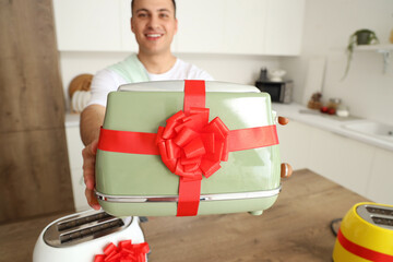 Wall Mural - Young man with gift toaster in kitchen, closeup