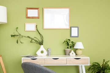 Wall Mural - Vase with eucalyptus branches and lamp on table near green wall in room