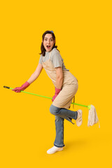 Wall Mural - Pretty woman having fun with mop on yellow background