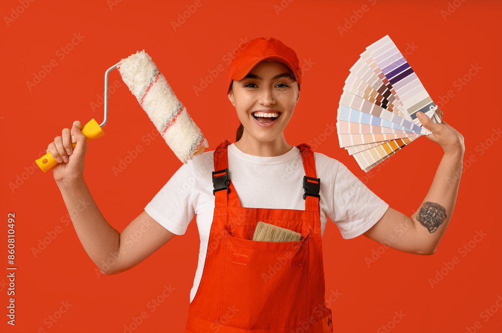 Female painter with color palettes and paint roller on red background