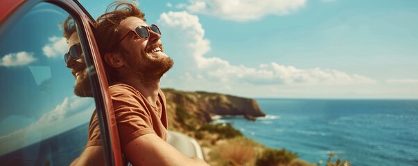 Carefree young man is leaning out of car window and enjoying road trip by the sea