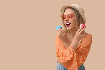 Poster - Beautiful young woman with sweet macaroons on beige background