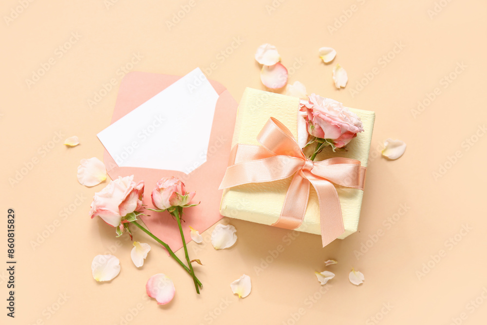 Envelope with blank card, gift box and roses on beige background