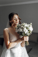 Wall Mural - A bride is wearing a white dress and veil, and is standing in front of a curtain. The image has a romantic and intimate mood, as the bride is posing for a picture in front of the curtain