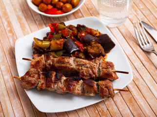 Wall Mural - Traditional georgian dish shish kebab or shashlik, grilled pork meat served with braised eggplants, pepper and tomatoes