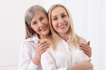 Wall Mural - Family portrait of young woman and her mother on white background