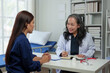 © crizzystudio - Asian elderly doctor explaining Advising Asian female patients about medicines in hospital Asking about illness history Health check and encouragement health insurance concept.