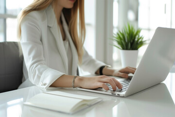 Wall Mural - A woman is sitting at a desk with a laptop.