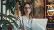 © Jaroon - A woman is sitting at a table with a laptop, creating a pleasant and relaxing atmosphere.