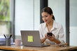 © Phimwilai - Asian businesswoman talking on the phone working in a modern office. Contacting customers. Customer manager, company sales. Contact online for finances startup business idea.