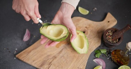 Wall Mural - Woman peeling Halved green avocado fruit while cooking at domestic kitchen