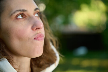 Crop view of female face. Portrait of a smiling brunette girl with red lips. Close up view of the lips. Woman walking in the park.