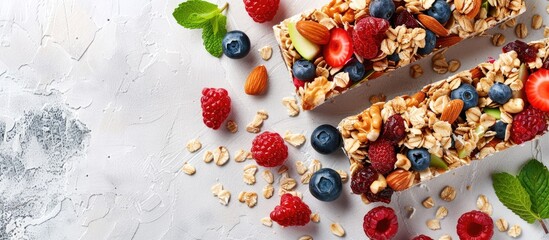 Wall Mural - Granola bar and ingredients on a white stone table. Cereal granola bar with nuts, fruit and berries. Top view long banner format. with copy space image. Place for adding text or design