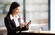 © NAMPIX - Beautiful asian businesswoman sit in the cafe, using smartphone and smiling. stock photo
