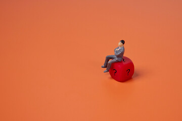 Businessman sitting on red dice with a question mark on orange background. Copy space for text. Luck, risk and choice concept.