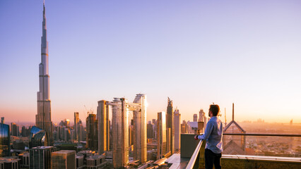 Man looking to Dubai sunset with views to the city centre from a skyscraper