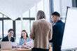 © Witoon - In a corporate meeting, a businessman leads a discussion on financial strategy, pointing at charts and graphs. The team collaborates on planning and analysis, using laptops and paperwork to ensure suc